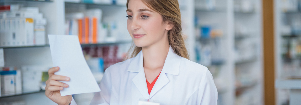 A skilled and experienced allied health professional (AHP), possibly a pharmacist, reviewing a prescription in a well-stocked pharmacy. This image highlights the demand for experienced AHPs in the healthcare sector and how Hunter Gatherer AHP connects skilled professionals with rewarding opportunities.