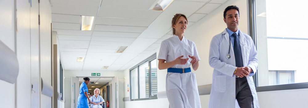 A diverse team of healthcare professionals, including doctors, nurses, and allied health professionals (AHPs), working together in a hospital corridor. Their collaboration represents the importance of teamwork in providing high-quality patient care. At Hunter Gatherer AHP, we focus on building resilient AHP teams to meet the growing demand for healthcare services and ensure improved patient outcomes through effective recruitment strategies.