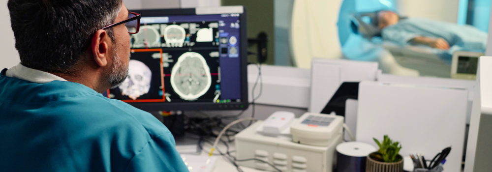 A radiographer placed by Hunter Gatherer AHP analysing brain MRI scans while a patient undergoes imaging, highlighting the impact of skilled locum AHPs in diagnostic care.
