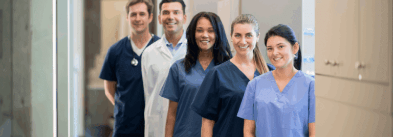 Group of smiling healthcare professionals standing together in a hospital corridor