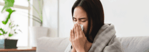 Woman with flu symptoms at home during winter, representing seasonal healthcare pressures in the UK