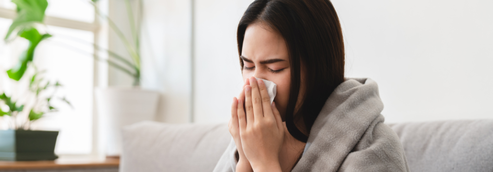 Woman with flu symptoms at home during winter, representing seasonal healthcare pressures in the UK